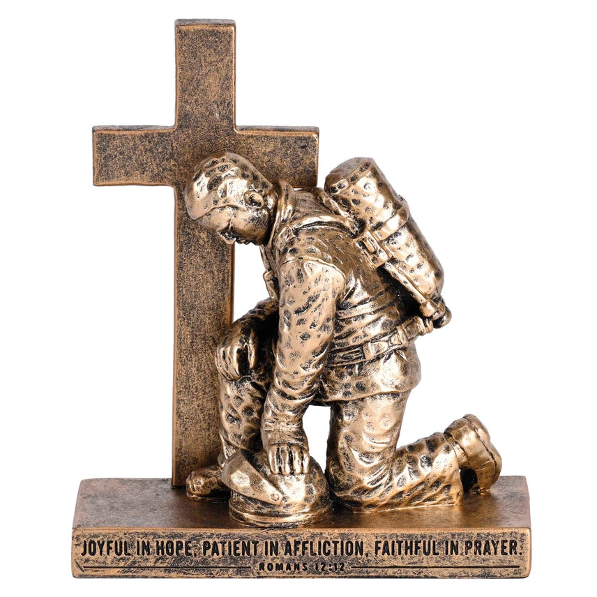 Kneeling firefighter prayer figurine beside a cross with Romans 12:12 engraving.